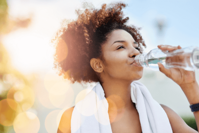 Woman drinking water to stay hydrated and prevent hemorrhoids naturally.